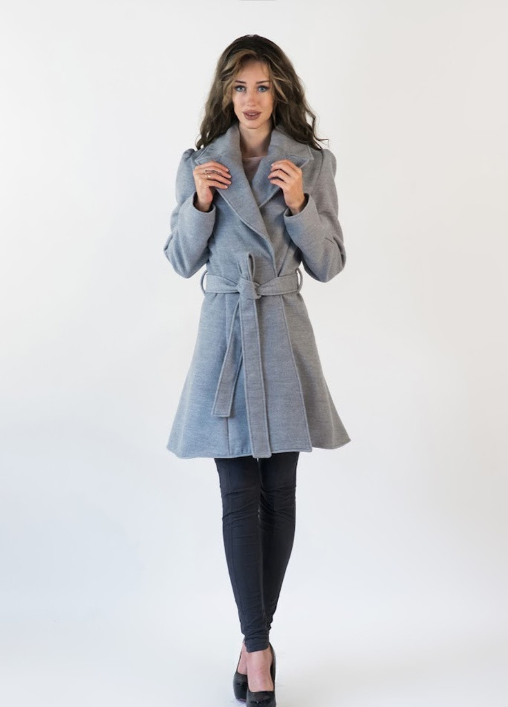 Жінка-модель на показі моди одягнена у пальто сірого кольору із хутровим коміром.